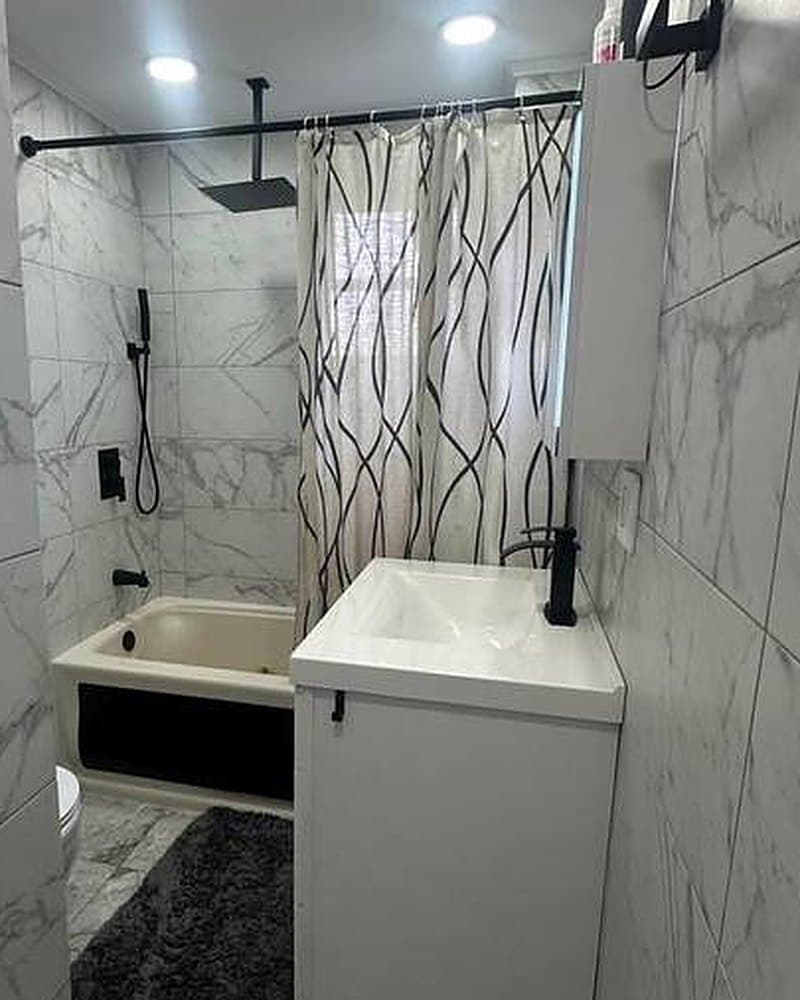Remodeled bathroom with large-format marble-look tile, soaking tub and matte black fixtures
