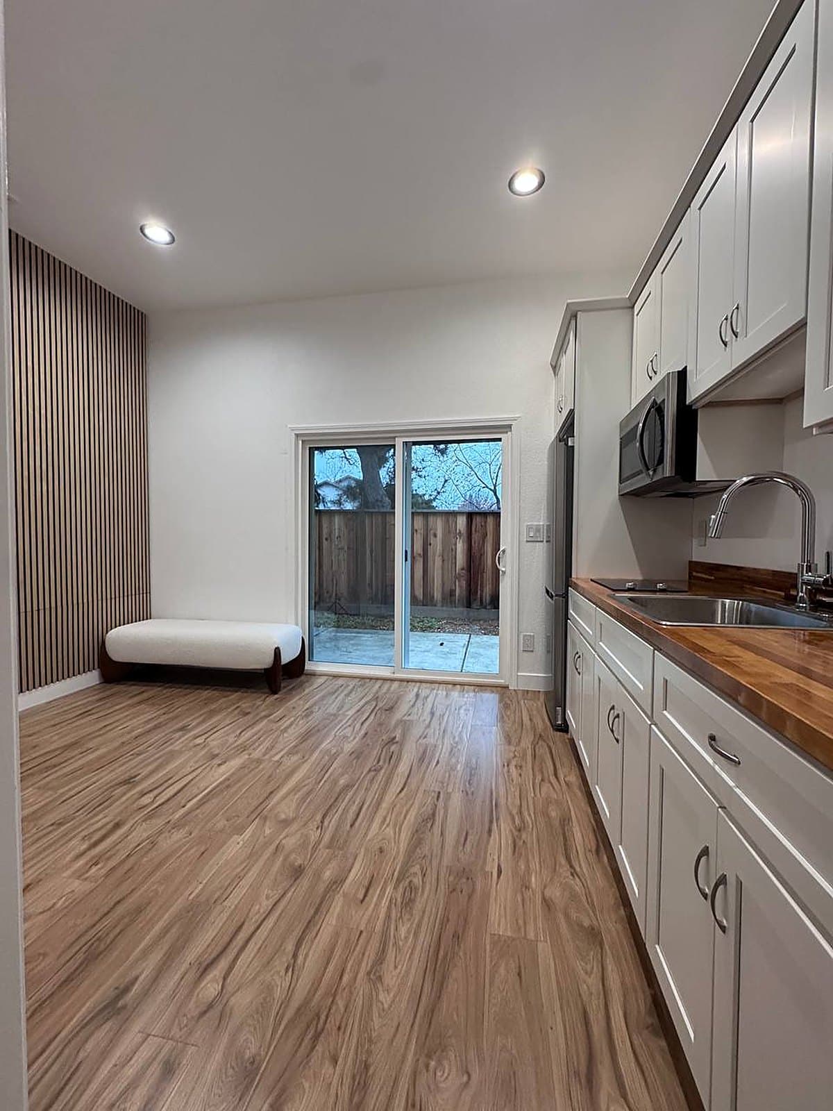 Remodeled living area with walnut slat wall, bench and sliding door to the patio