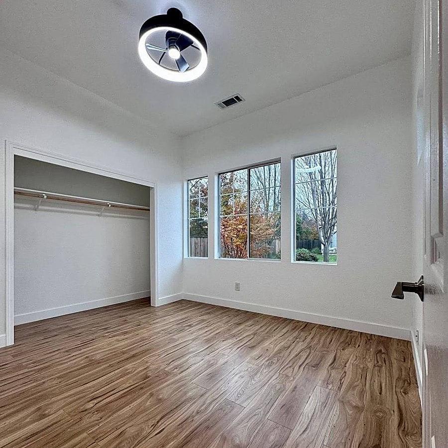 After: bright bedroom with plank flooring, open closet and modern ceiling light