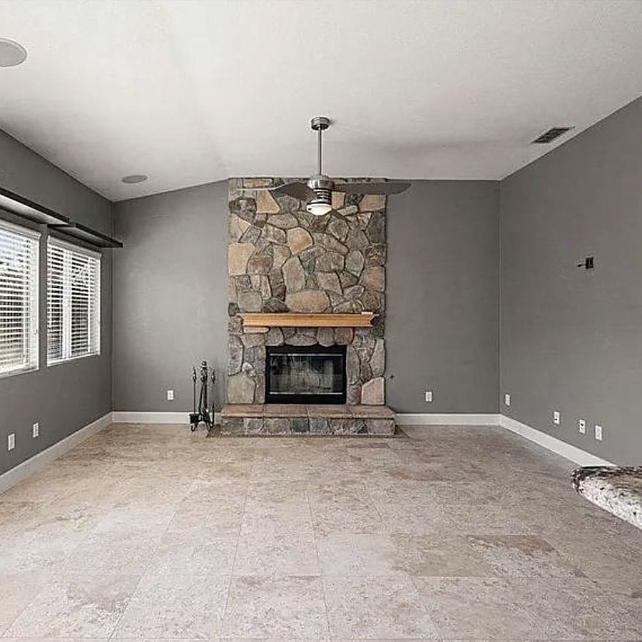 Before: living room with stone fireplace, grey walls and travertine tile floor