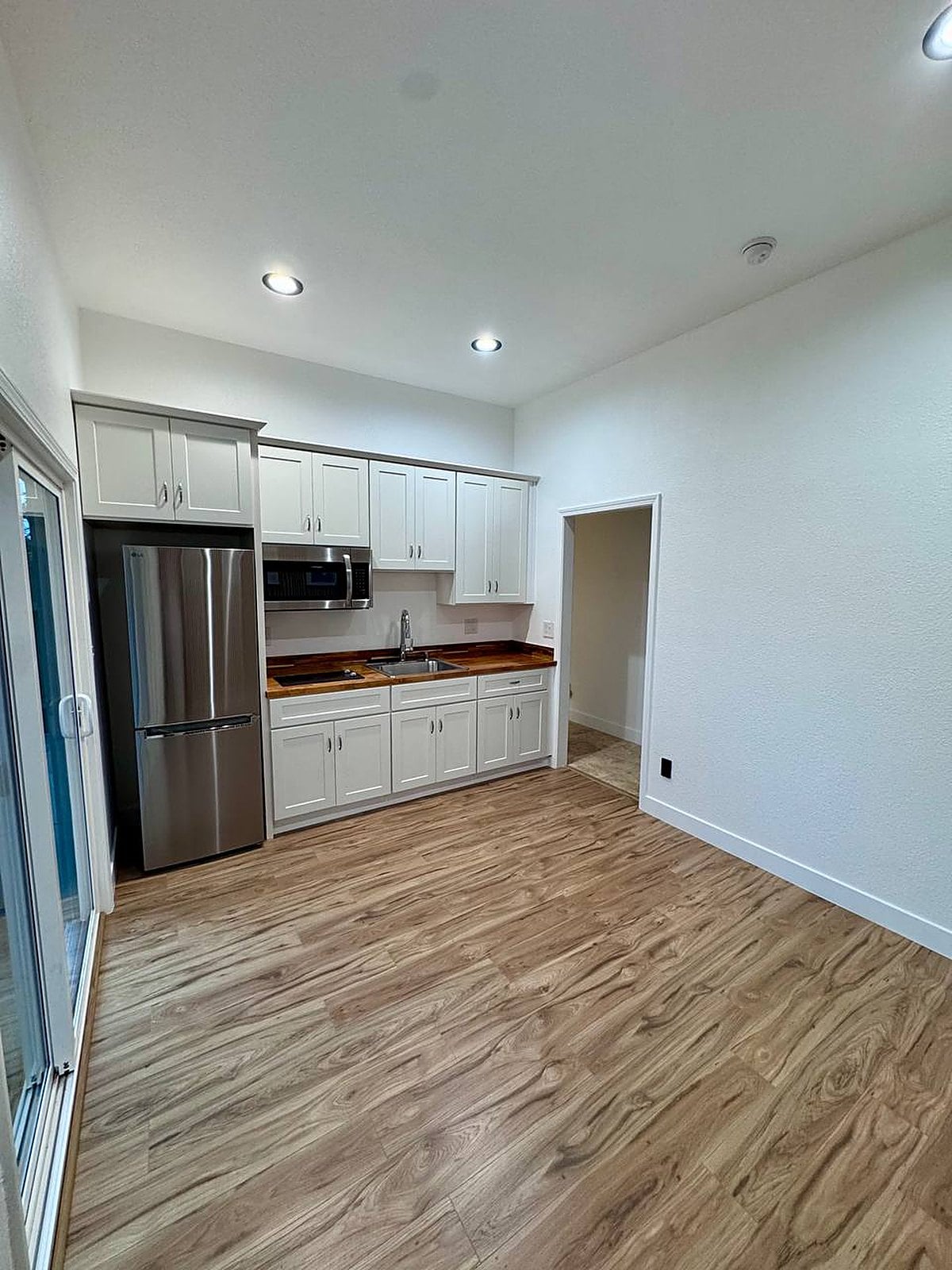 Remodeled kitchenette with wood-look plank flooring and white shaker cabinetry